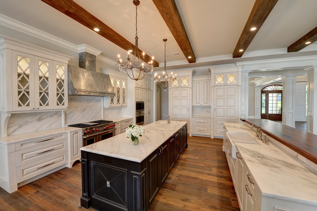 Large kitchen with white cupboards and countertops, with dark accented island