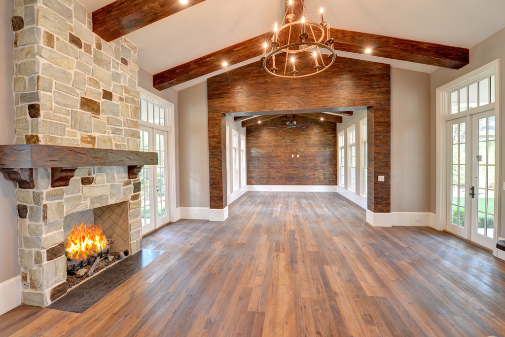 Interior of house with woods floor, wood ceiling beams, and stone fireplace