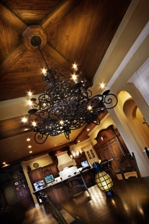 View of dining room and kitchen with dark wood pieces and stylized chandeliers