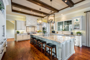 Kitchen with white cabinets, large island, and wood ceiling beams 