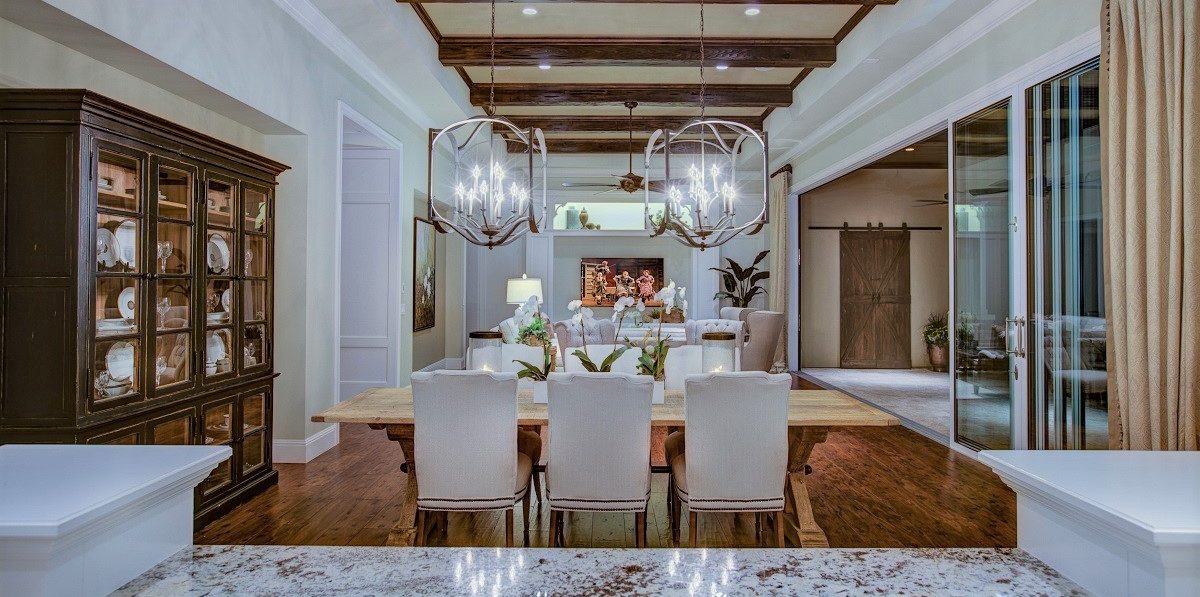 Large dining room leading into living room decorated with white and wood accents